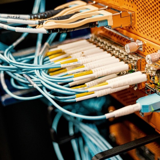 Fiber optic cables plugged into orange rack-mounted network equipment.