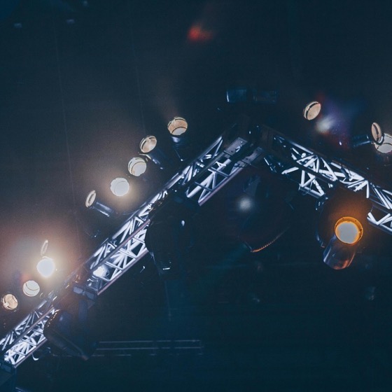 Stage lighting truss with spotlights and rigging suspended in a dark venue.